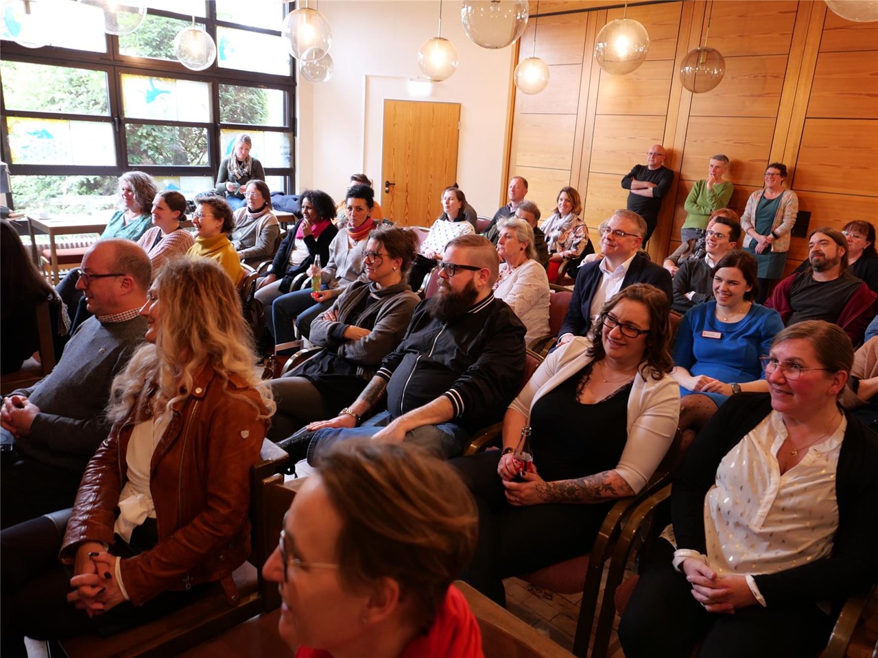 Menschen sitzen im Saal auf Stühlen.