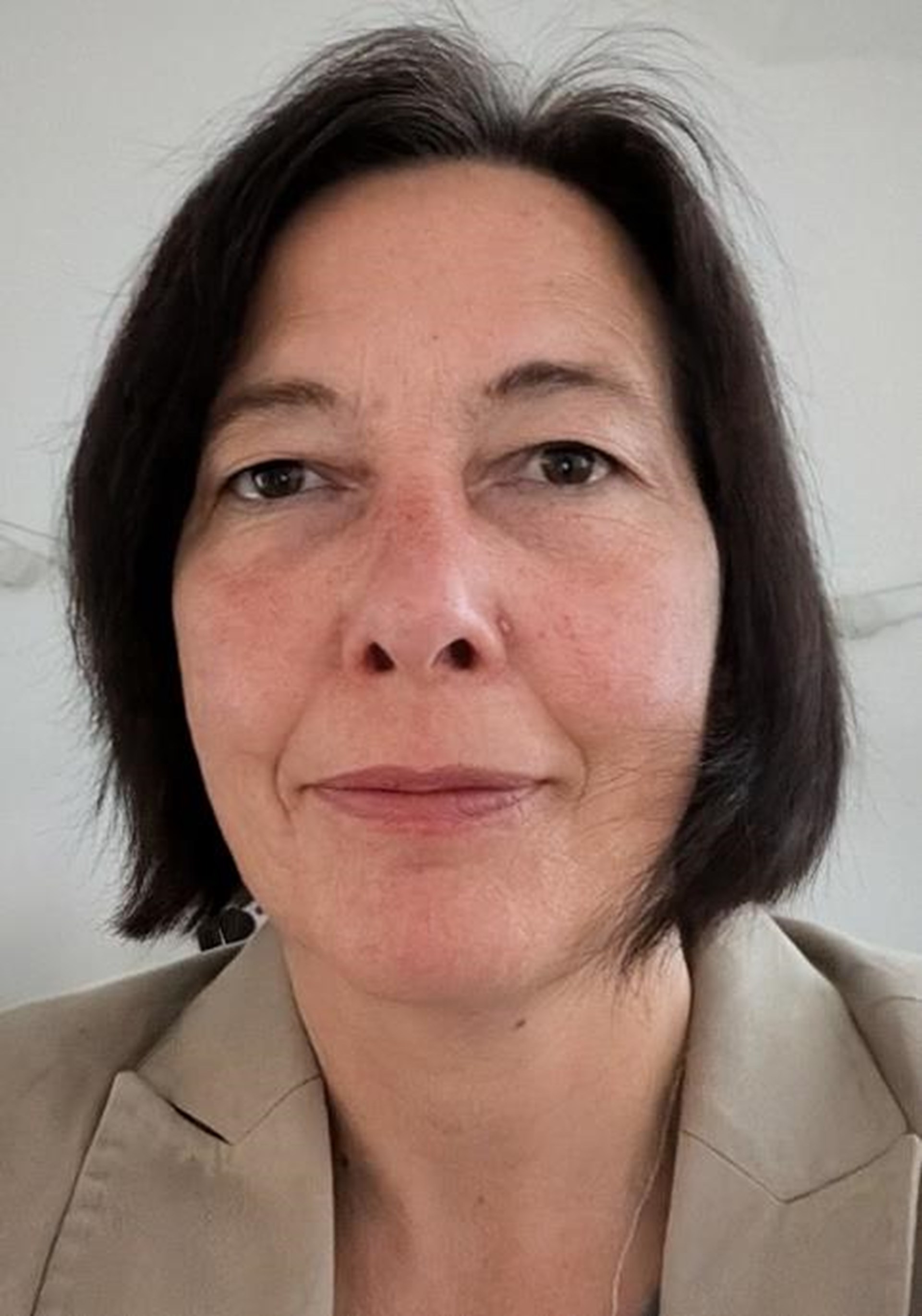 Frau mit dunklen kinnlangen Haaren im Porträt.