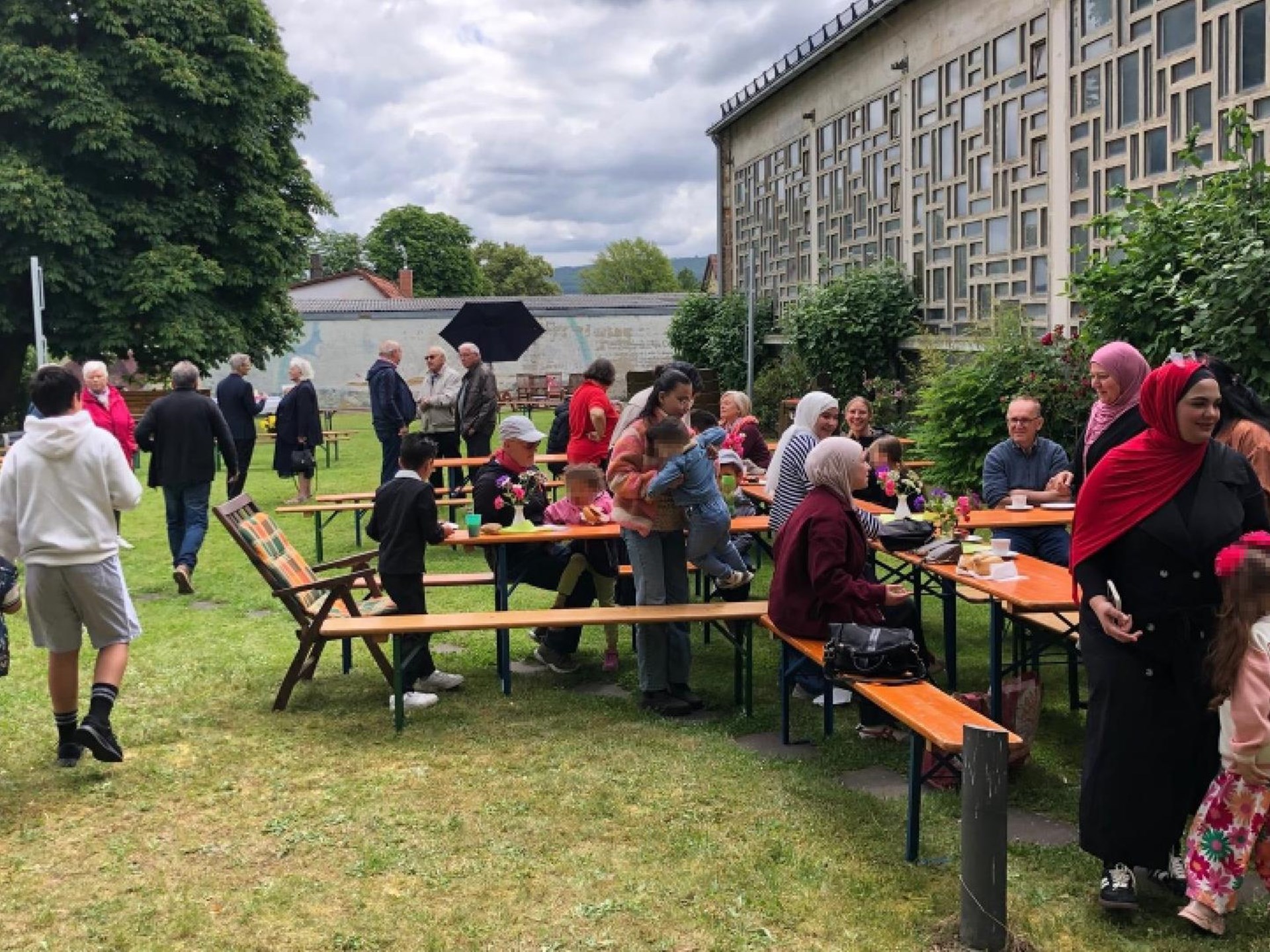 Menschen unterschiedlichen Alters und unterschiedlicher Herkunft feiern gemeinsam ein Gartenfest.