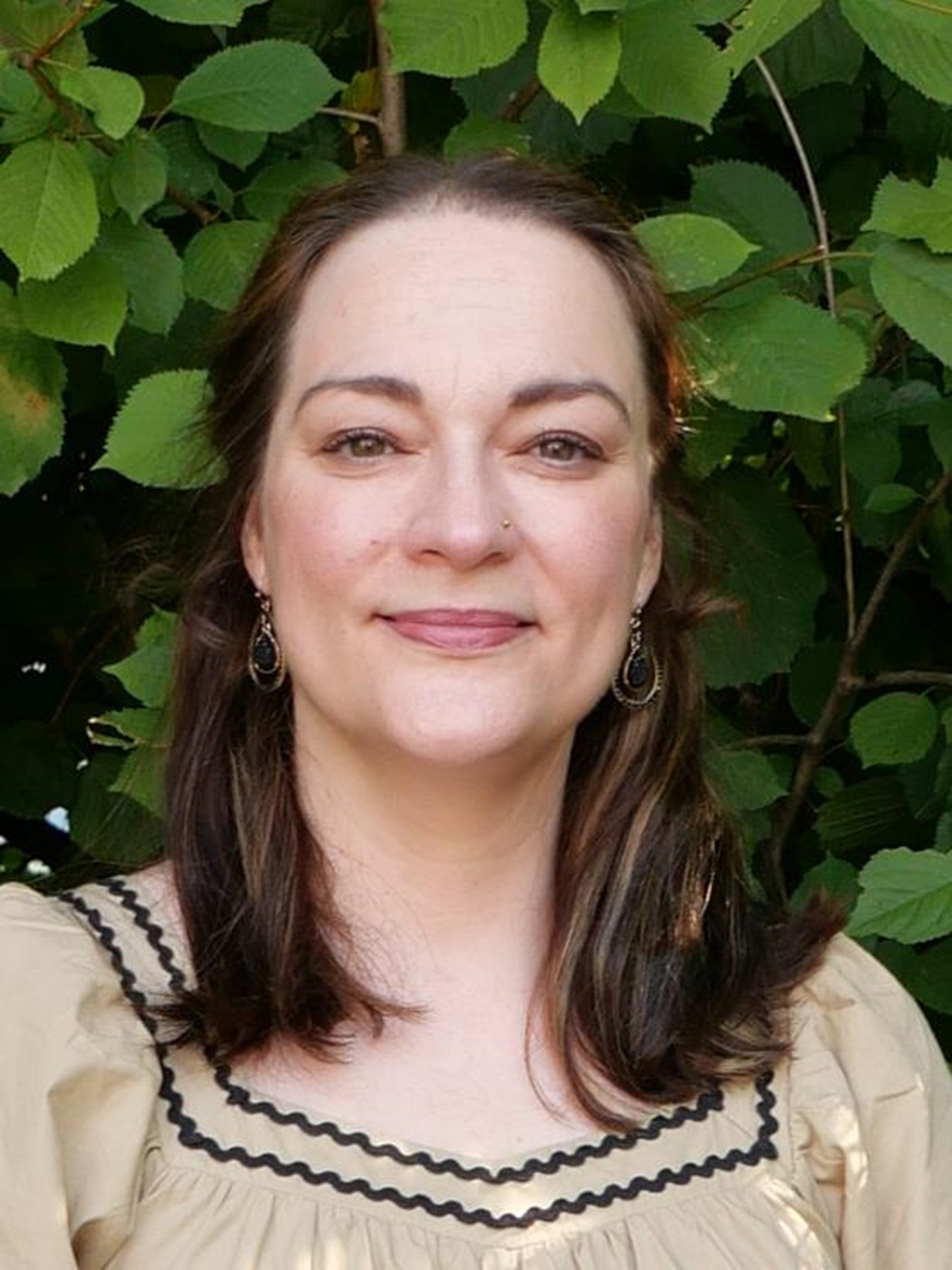 Frau mit dunklen langen Haaren schaut in die Kamera